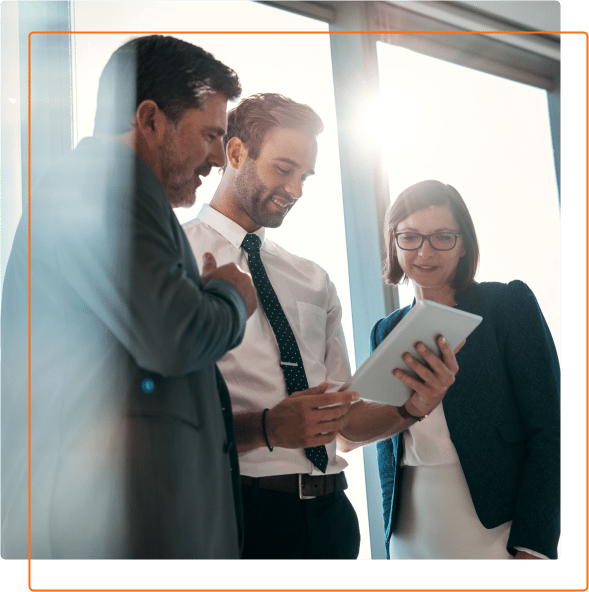 A group of professionals collaborates around a tablet, engaged in a discussion in a bright, modern office environment.