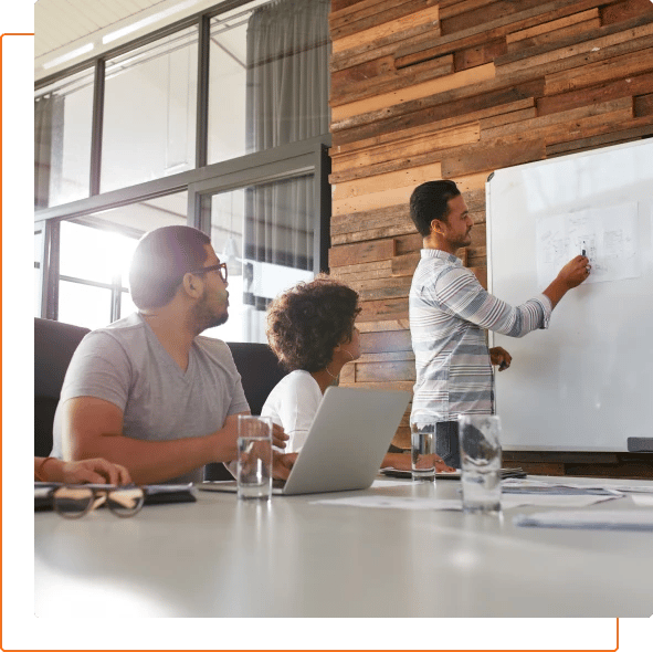 Photo of a team meeting with a man writing notes on a paper.