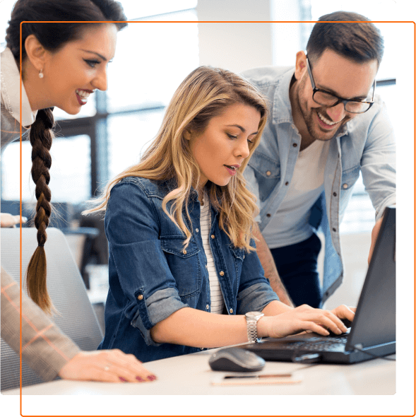 A group of people collaborates around a laptop in a modern office setting, focused on a project or discussion.