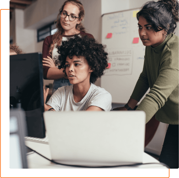 A diverse group of people collaborates in an office setting, focusing on a computer screen and sharing ideas.