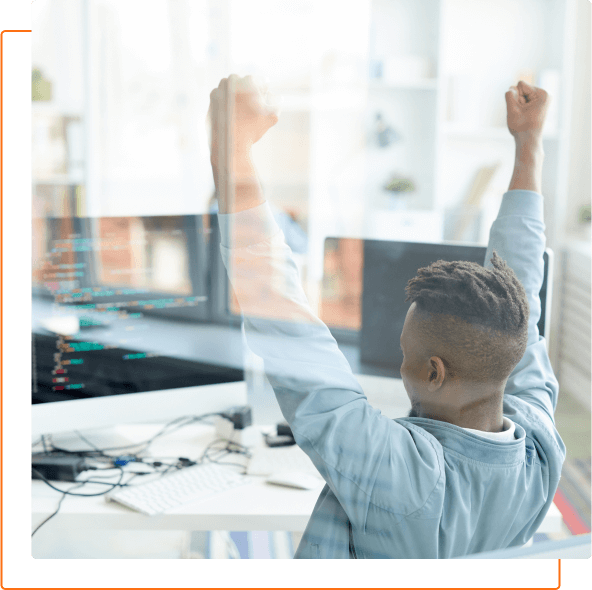 A person celebrating a successful project in a bright office, with arms raised and a joyful expression, in front of multiple computer screens.